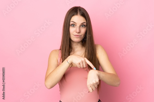 Young caucasian woman isolated on pink background making the gesture of being late