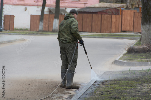 A worker washes the road curb with water.