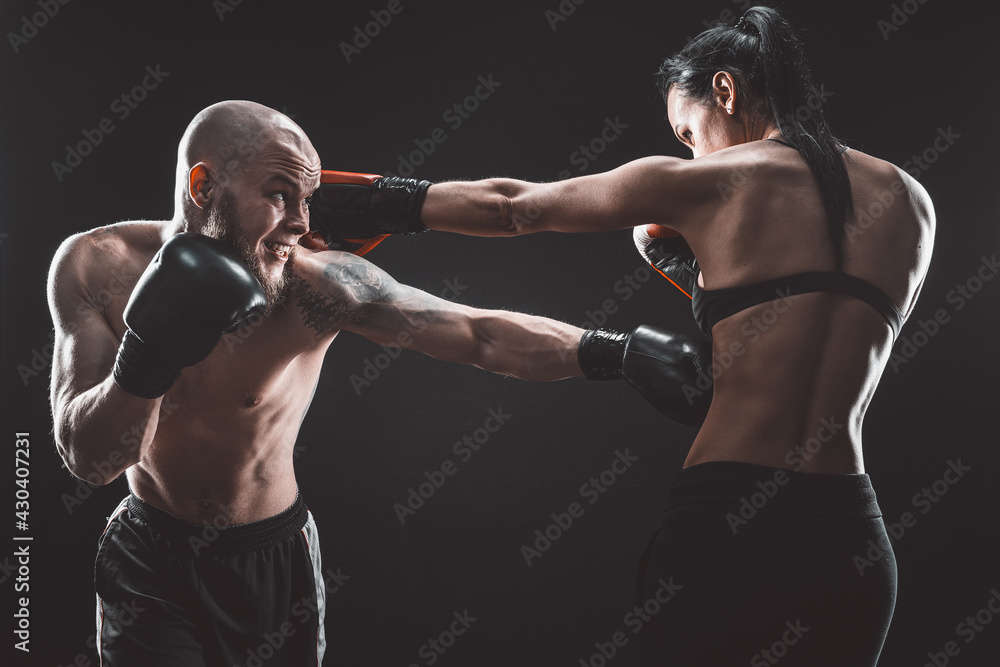 Shirtless Woman exercising with trainer at boxing and self defen