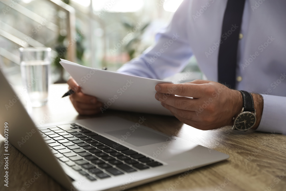 Businessman working with documents at wooden desk in office, closeup Businessman working with documents at wooden desk in office, closeup