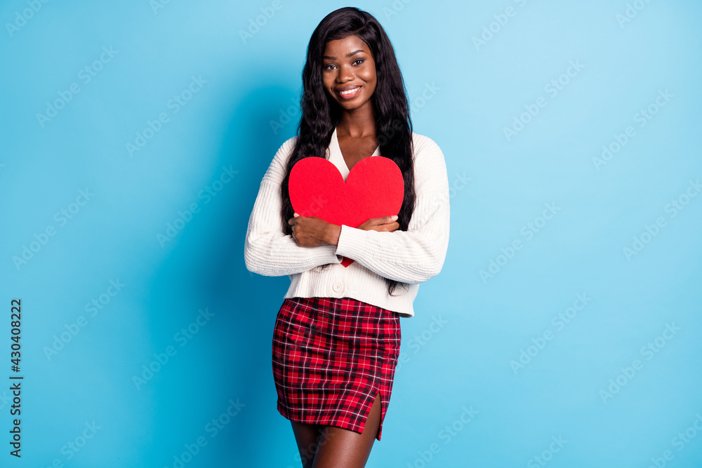 Photo of pretty charming dark skin woman hold hug big red paper heart isolated on blue color background Photo of pretty charming dark skin woman hold hug big red paper heart isolated on blue color background