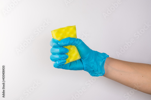 Sponge for washing dishes in female hand. Hand in a latex glove. Woman's hand gesture or sign isolated on white. A hand in a glove holds a sponge for washing and cleaning dishes