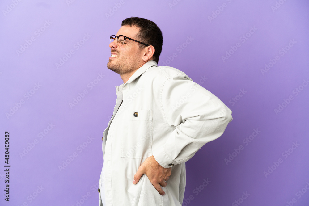 Brazilian man over isolated purple background suffering from backache for having made an effort Brazilian man over isolated purple background suffering from backache for having made an effort