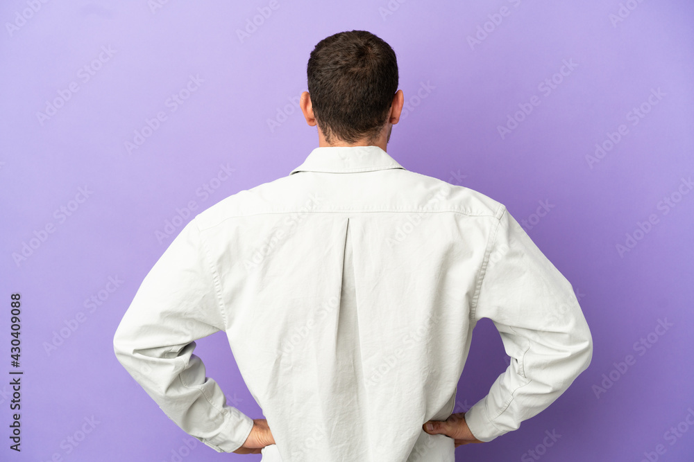 Brazilian man over isolated purple background in back position Brazilian man over isolated purple background in back position
