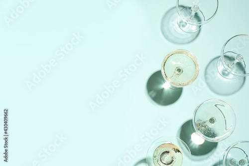 Set of empty glasses on light blue background, flat lay. Space for text