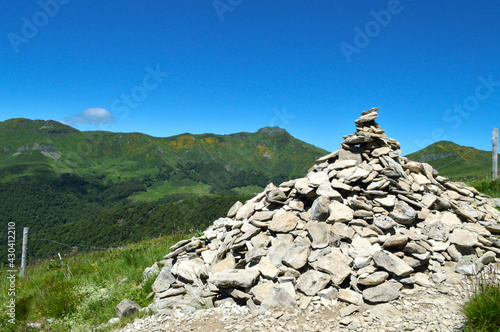A cairn made by hikers on top of a mountain in front of a mountain landscape © jpr03