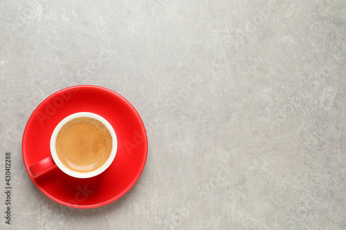 Aromatic coffee in red cup on light grey background, top view. Space for text