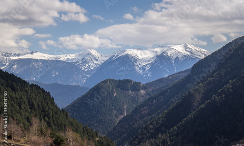 photo of the snowy Pyrenees of Andorra through forest and trails under blue sky © gaston