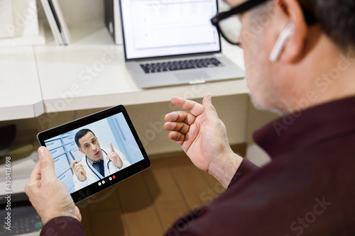 Video chiamata tra un paziente e un medico curante attraverso un tablet  in contesto casalingo photo