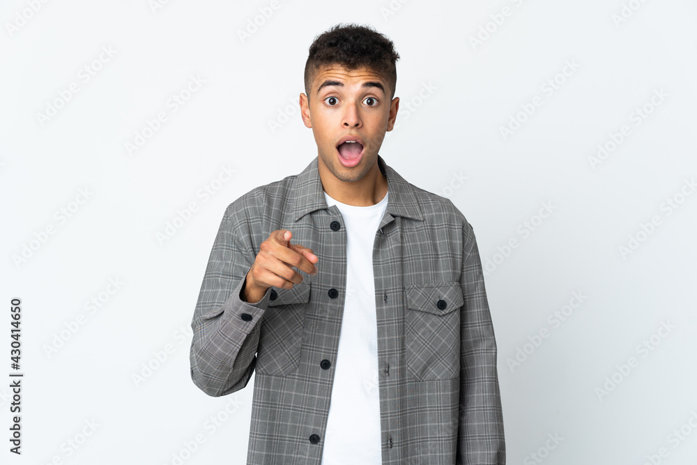 Young brazilian man isolated on white background surprised and pointing front Young brazilian man isolated on white background surprised and pointing front