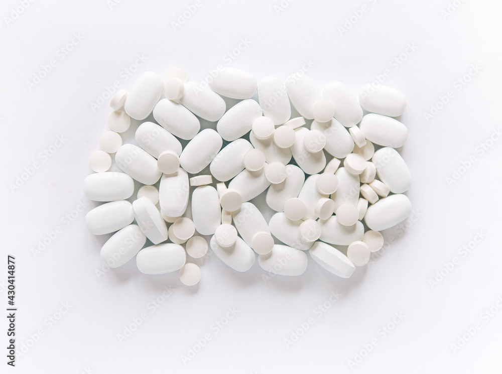 White pills on a white background. Oblong and round pills close-up. Healthcare and medicine. White pills on a white background. Oblong and round pills close-up. Healthcare and medicine.