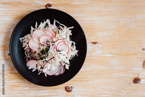 Coleslaw with radish on black plate viewed from above