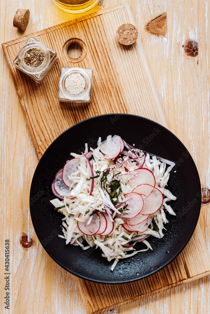 Coleslaw with radish on black plate viewed from above