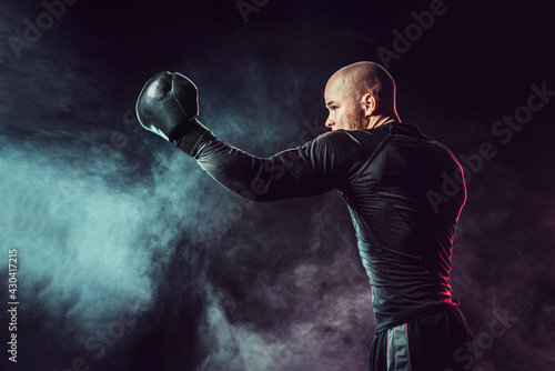 Sportsman boxer fighting, hitting uppercut on black background w