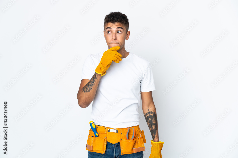 Young Brazilian electrician manipulated isolated on white background having doubts and thinking Young Brazilian electrician manipulated isolated on white background having doubts and thinking