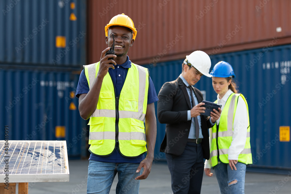 African factory worker or engineer using walkie talkie for preparing a job in containers warehouse storage