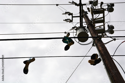 Several pairs of old running shoes dangle from the power lines