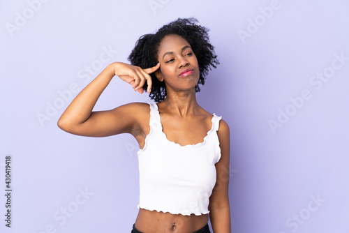 Young African American woman isolated on purple background making the gesture of madness putting finger on the head © luismolinero
