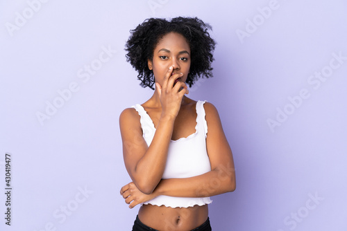 Young African American woman isolated on purple background surprised and shocked while looking right