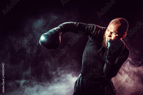 Sportsman boxer training, hitting side impact on black backgroun