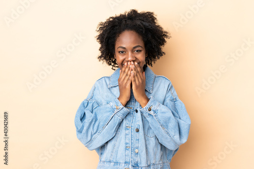 Young African American woman isolated on beige background happy and smiling covering mouth with hands