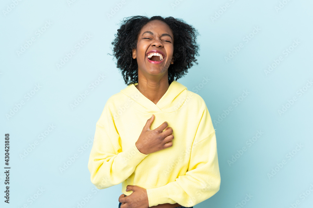 Young African American woman isolated on blue background smiling a lot Young African American woman isolated on blue background smiling a lot