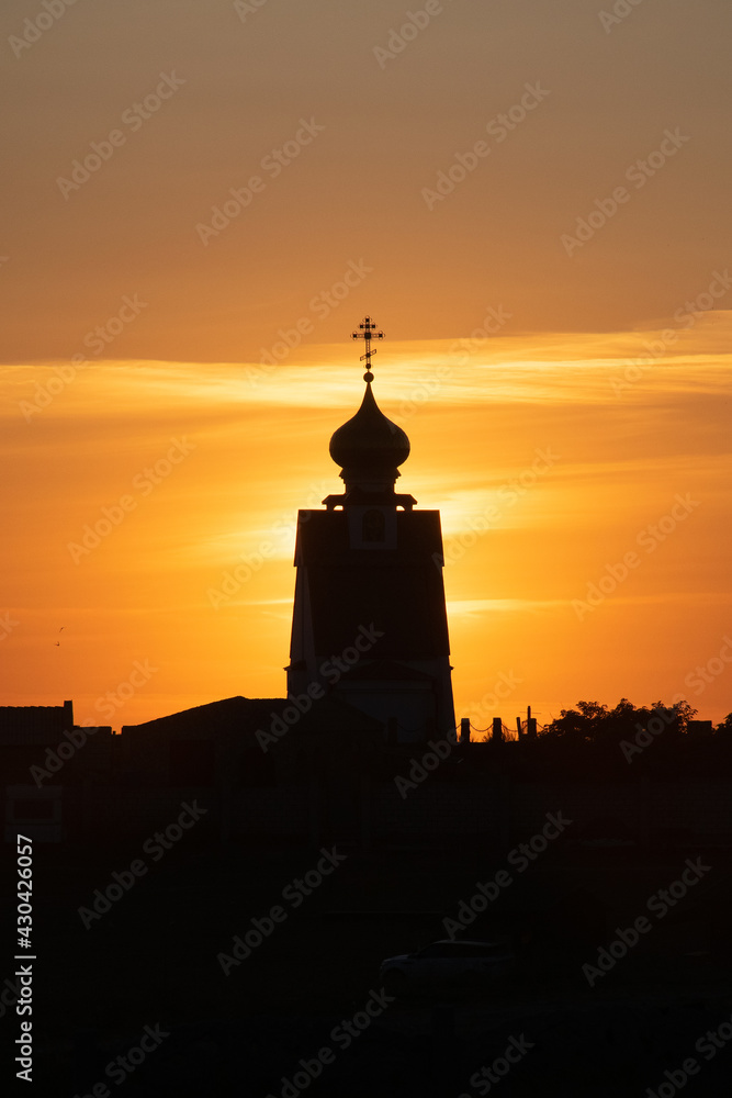 Orthodox Church with gilded domes on the background of a fiery sunset in the village of Bolshoy Atlesh on the Crimean cape Tarkhankut.