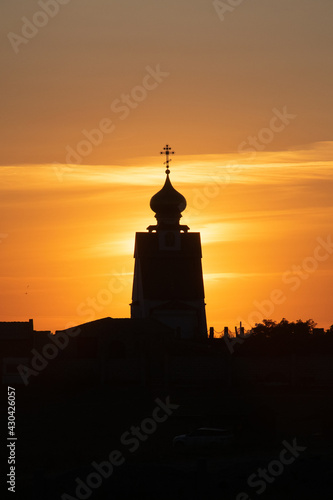 Orthodox Church with gilded domes on the background of a fiery sunset in the village of Bolshoy Atlesh on the Crimean cape Tarkhankut.