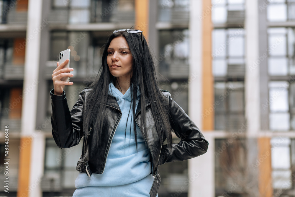 Young beautiful brunette girl on the street makes a selfie on the phone
