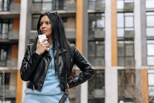 Young woman using mobile phone. Beautiful brunette woman using smartphone and looking away, thinking about something . Technology concept