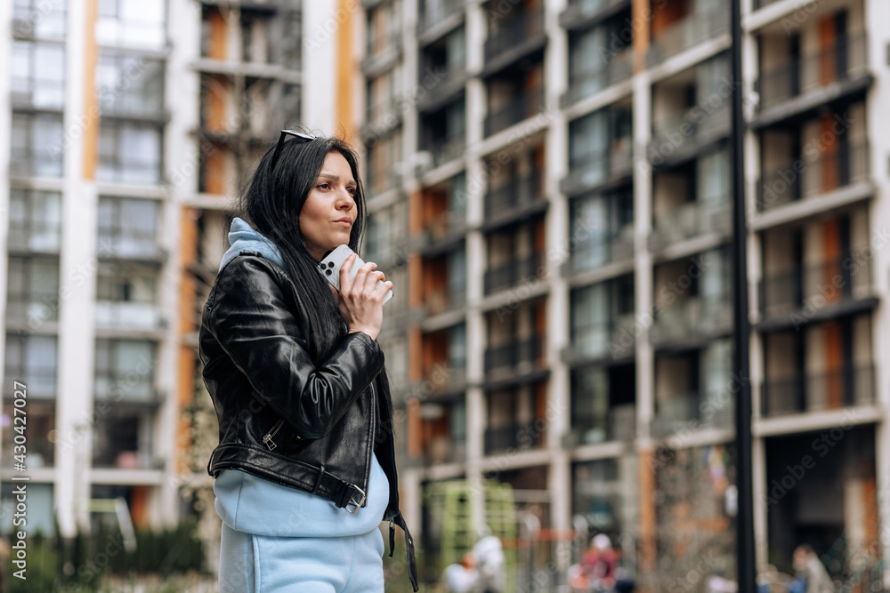 Young woman using mobile phone. Beautiful brunette woman using smartphone and looking away, thinking about something . Technology concept