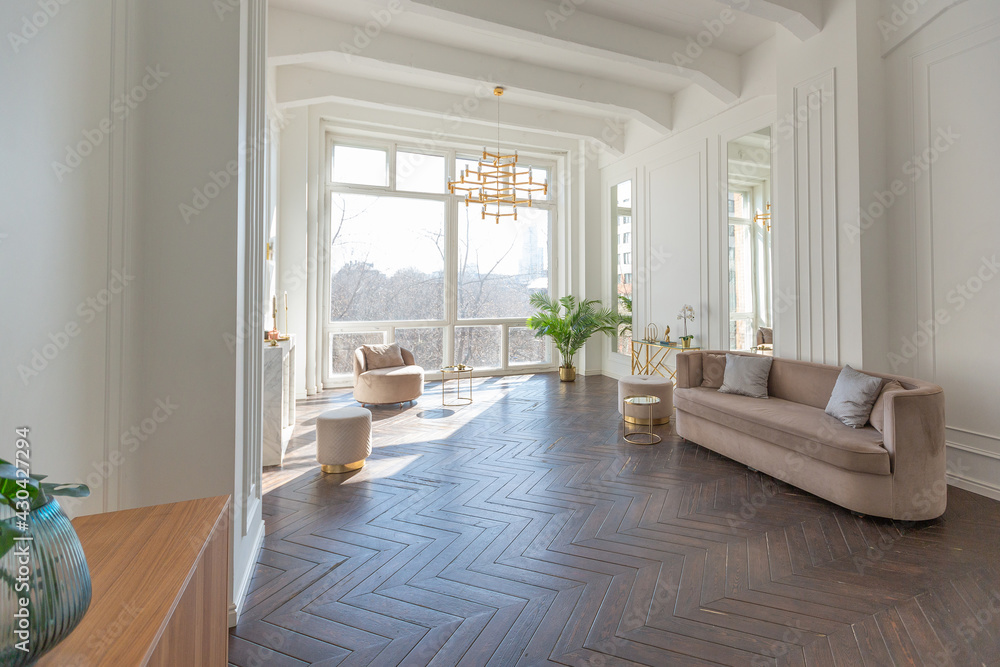 very light and bright interior of luxurious cozy living room with chic soft beige furniture with gold metallic elements, huge window to the floor and wooden parquet very light and bright interior of luxurious cozy living room with chic soft beige furniture with gold metallic elements, huge window to the floor and wooden parquet