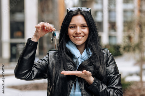 Young brunette girl happily demonstrates the keys to her new home
