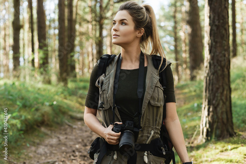 Woman hiker walking with a backpack and modern mirrorless camera