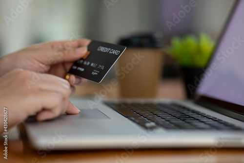Close up woman hand using credit card and smartphone laptop for buying online shopping