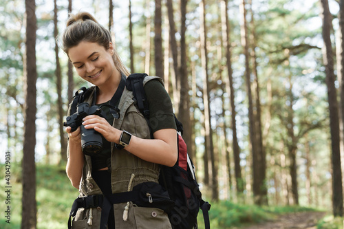 Hiker using modern mirrorless camera in green forest