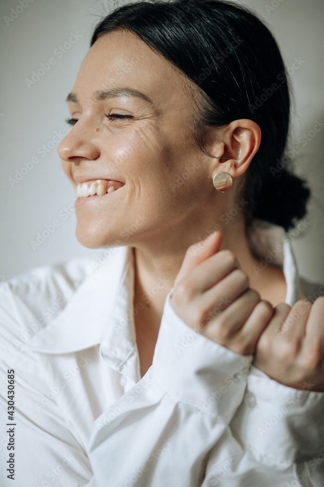Beautiful brunette with gathered hair smiles in a white shirt. Portrait Beautiful brunette with gathered hair smiles in a white shirt. Portrait