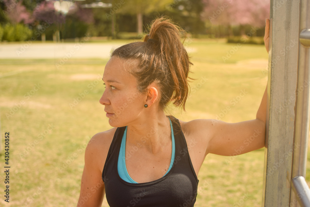 White Caucasian woman with her hair tied up doing stretching exercises in the park. Concept of outdoor exercise, wellness, health. White Caucasian woman with her hair tied up doing stretching exercises in the park. Concept of outdoor exercise, wellness, health.
