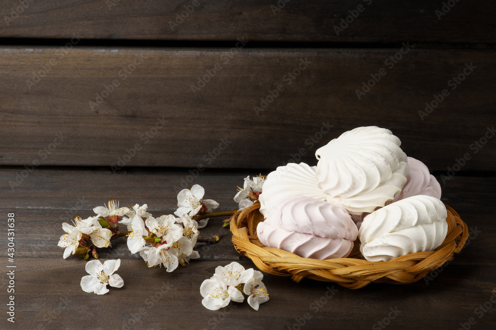 marshmallow. meringue decorated with a white flower on a dark wood background.
