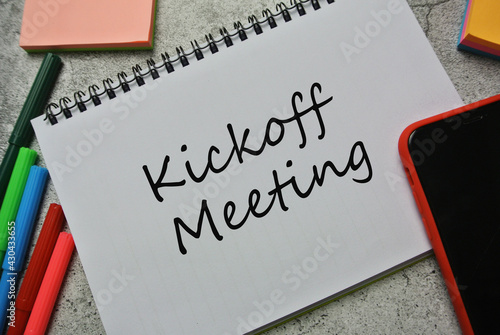 Top view of sticky note, marker pen, smart phone and notebook written with Kickoff Meeting.
