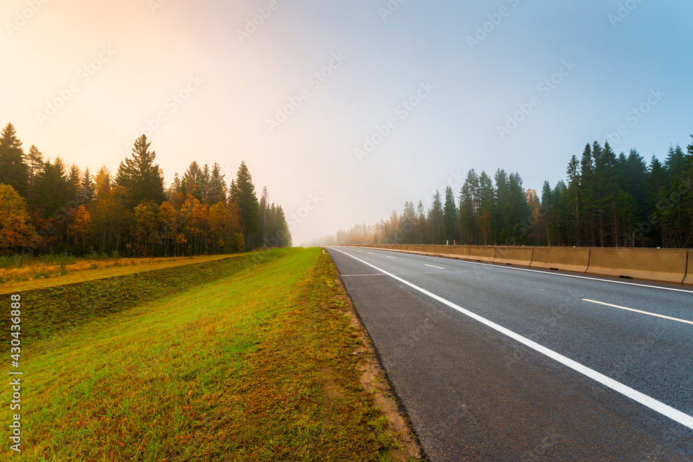 Suburban autumn highway. Coniferous forest in the fog. Sunrise. Autumn morning. View from the side of the road. Russia, Europe. Beautiful nature. Suburban autumn highway. Coniferous forest in the fog. Sunrise. Autumn morning. View from the side of the road. Russia, Europe. Beautiful nature.