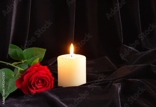 Obraz na plátne A burning candle and a red rose on a black background