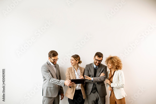 Multiethnic business people using digital tablet while standing by the wall in the office