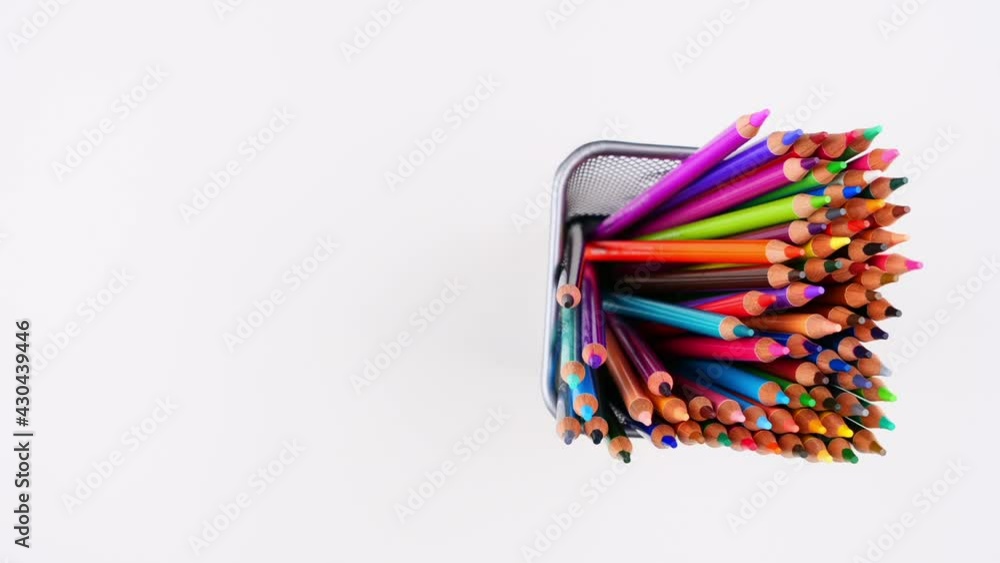Many colored pencils standing in metal pen holder on white desk. Top view. Stop motion animation. 4K Many colored pencils standing in metal pen holder on white desk. Top view. Stop motion animation. 4K