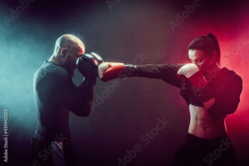 Woman exercising with trainer at boxing and self defense lesson