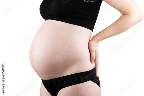 Pregnant woman in dress holds hands on belly on a white background. Pregnancy, maternity, preparation and expectation concept. Close-up, copy space