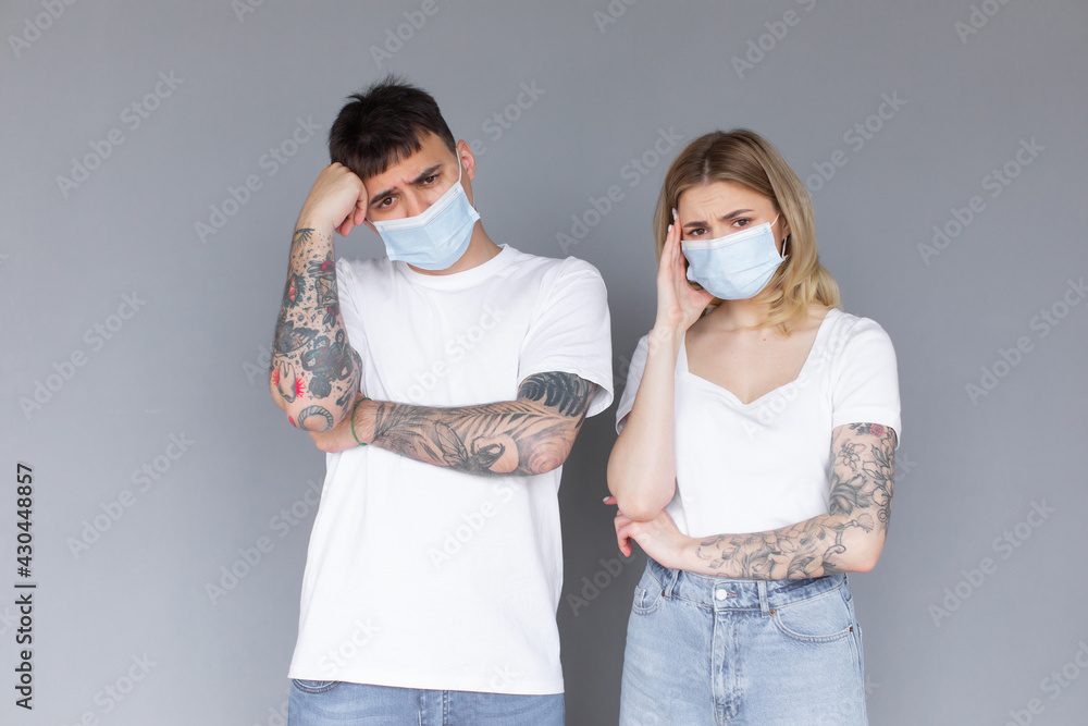 Young excited couple in protective masks isolated over gray background