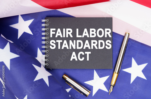 On the table is an American flag, a pen and a notebook with the inscription - FAIR LABOR STANDARDS ACT