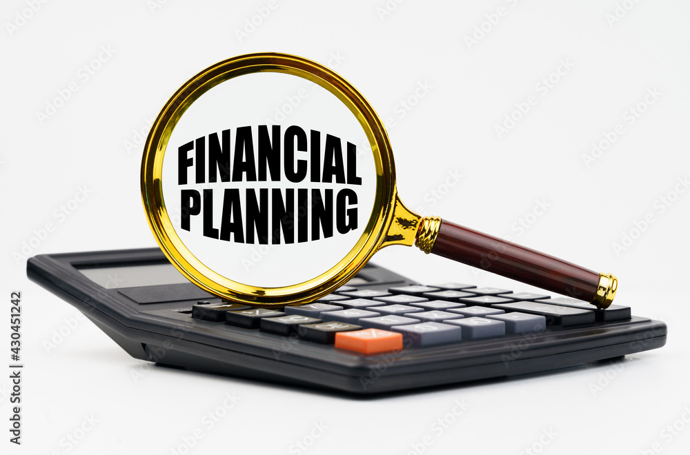 On a white background lies a calculator and a magnifying glass with the inscription - Financial planning On a white background lies a calculator and a magnifying glass with the inscription - Financial planning