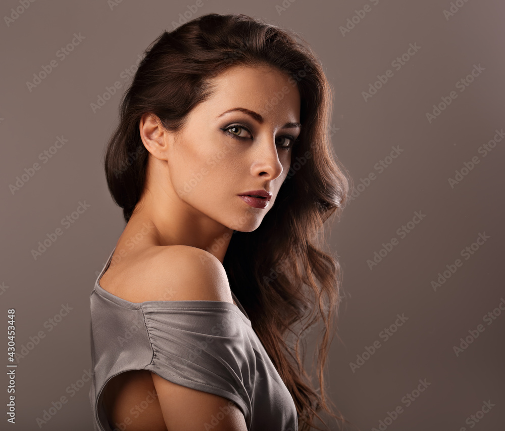 Beautiful mysterious woman makeup face and healthy volume brown hair with wisdom emotional look on brown color background. Closeup Beautiful mysterious woman makeup face and healthy volume brown hair with wisdom emotional look on brown color background. Closeup